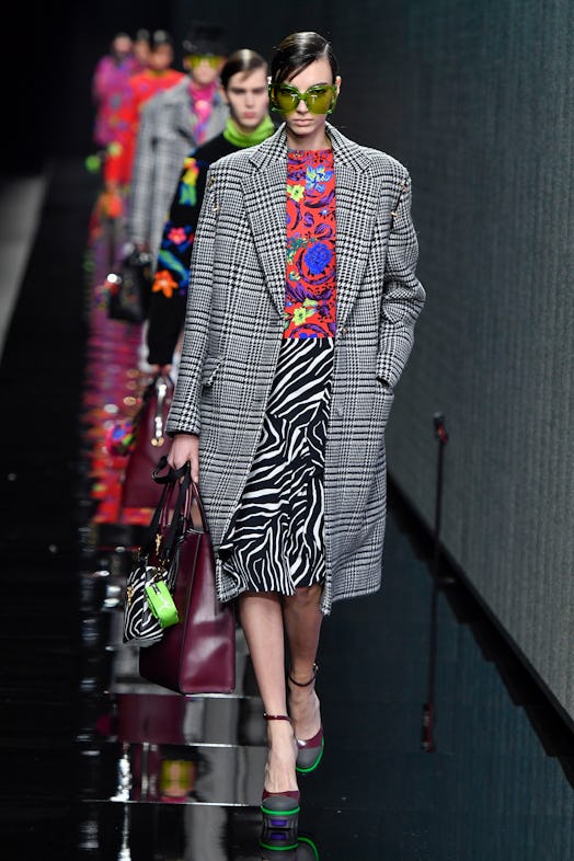 A model walking the runway in zebra print skirt, a floral pattern top and a grey check coat at the A...