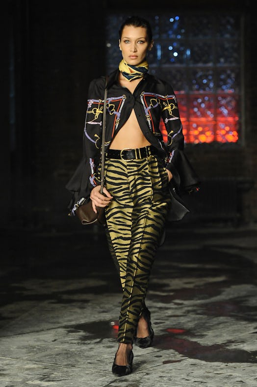 Bella Hadid wearing Versace's zebra print pants and an unbuttoned black shirt with golden chain deta...