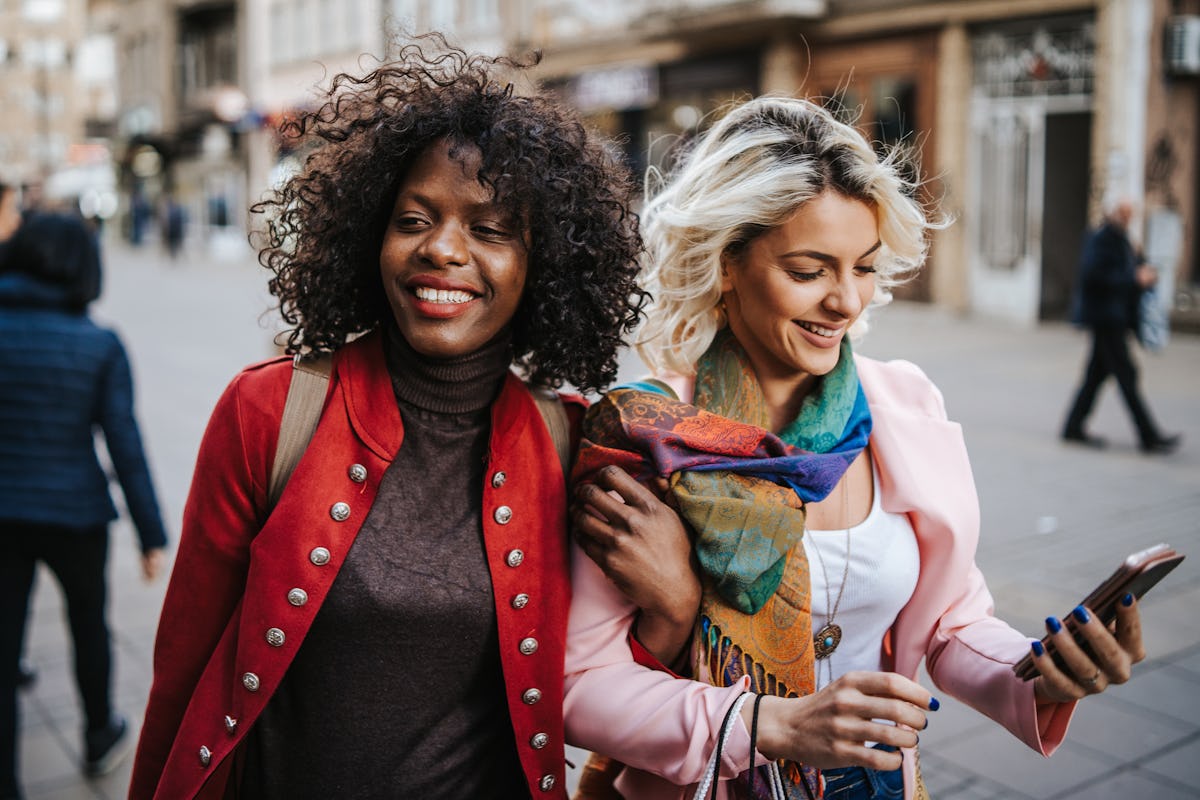 A young couple walks around in the city in colorful blazers and laughs on a chilly day.