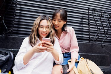 Two friends hang out in the city and look at their phones on Leap Day.