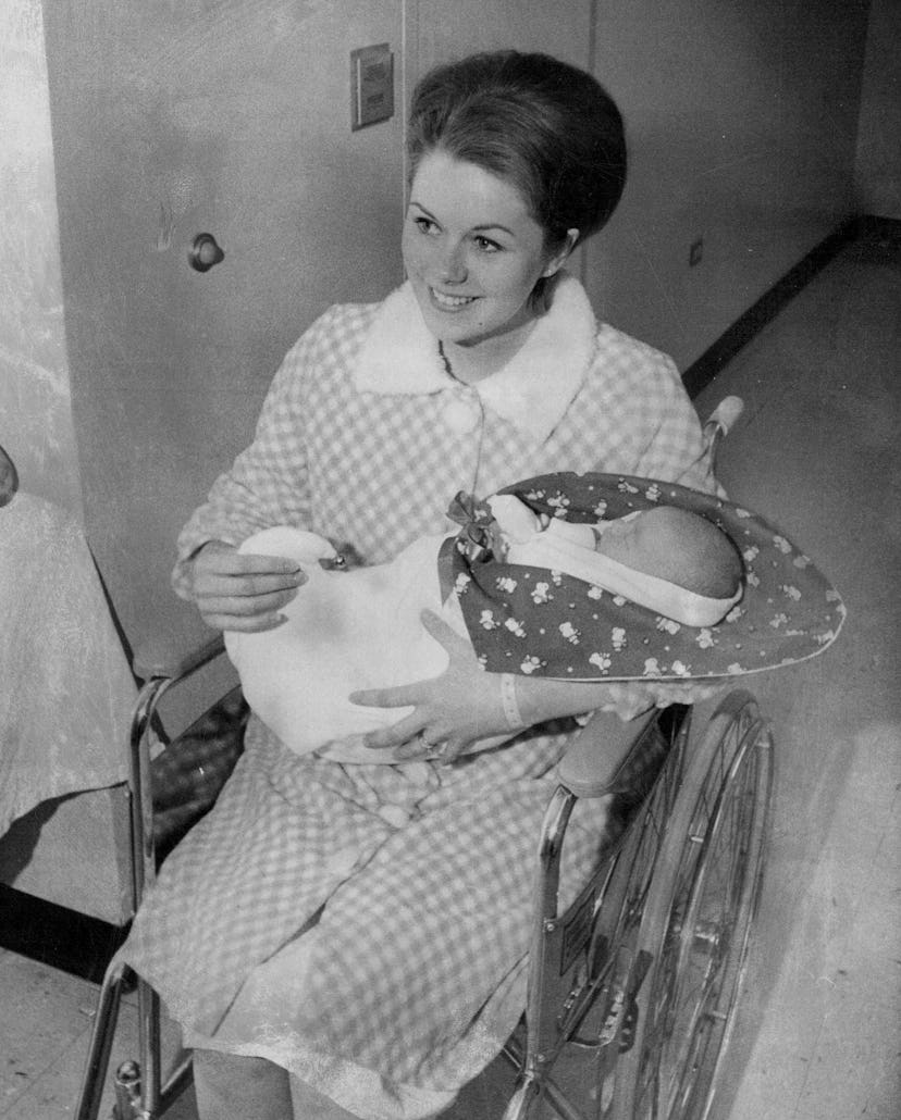 This mom wheels her baby home from the maternity ward in a snowman blanket on Christmas Day 1968.