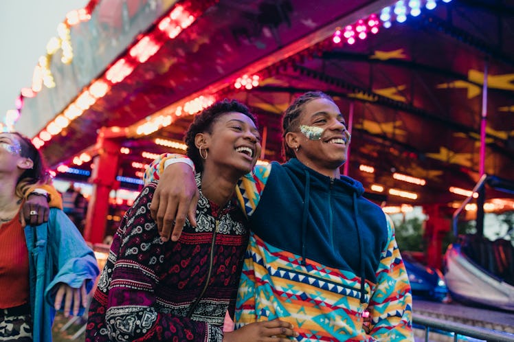 A couple walks through neon lights and arcade games during a birthday celebration.