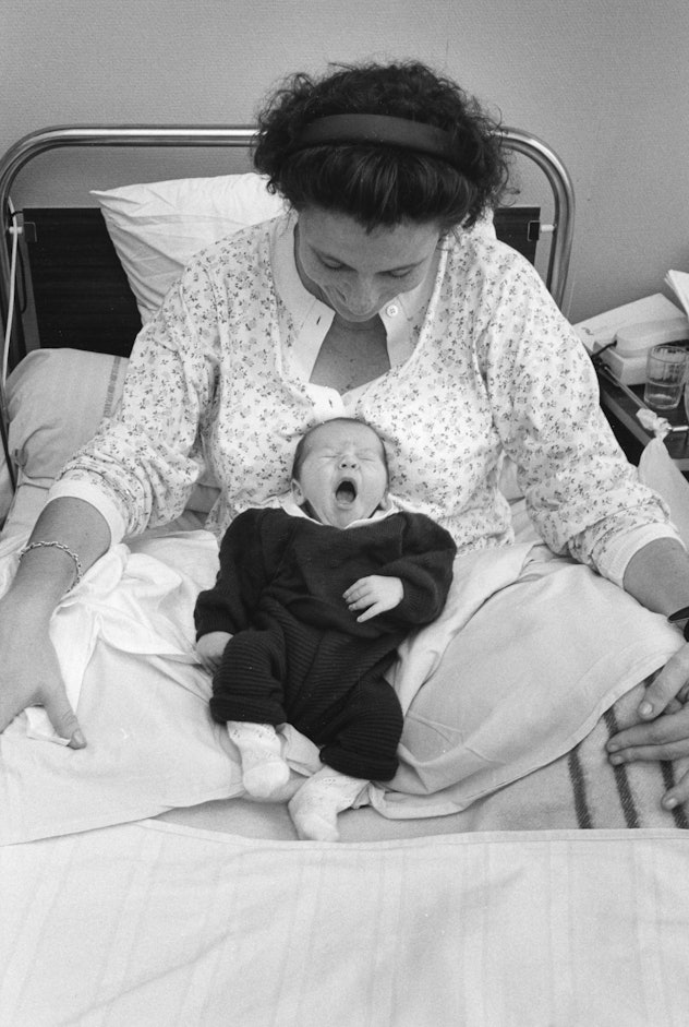 This mom's brand new baby yawns adorably as they nestle into her lap in the hospital bed.