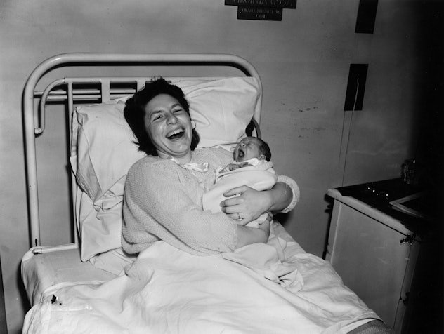 This 1950s mom is so overjoyed with her newborn baby, she looks like she's laughing out loud in this...