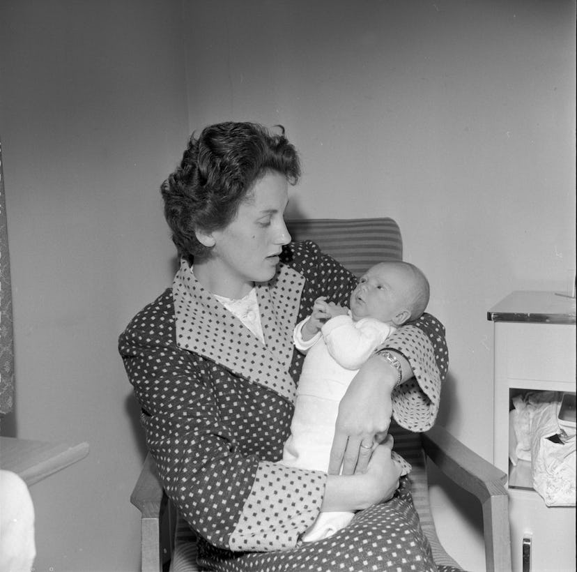 This 1957 mom in her polka dot robe looks like she's getting a real good look at her brand new baby ...
