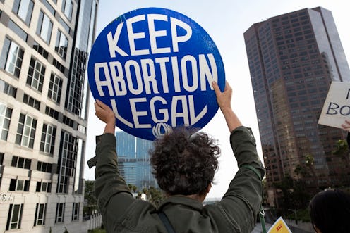 People standing in a crowd holding signs reading, "Keep Abortion Legal." Virginia lawmakers just rem...