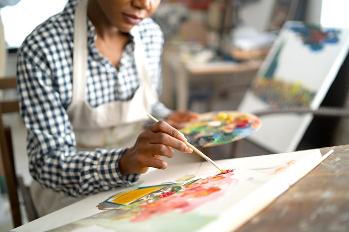 a woman painting a picture of flowers