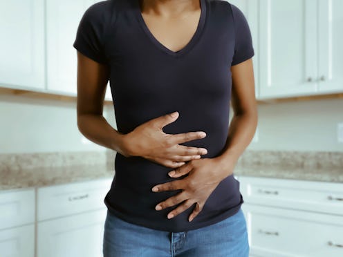 A woman holds her abdomen. Adenomyosis, which causes the lining of the uterus to fold into the outer...