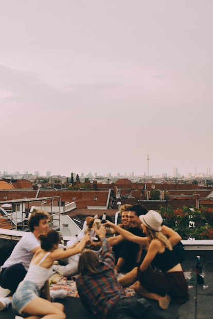 A group of friends celebrates a birthday while on a rooftop in the city.