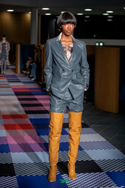 Model wears grey leather suit paired with cognac over-the-knee boots by MUNTHE 