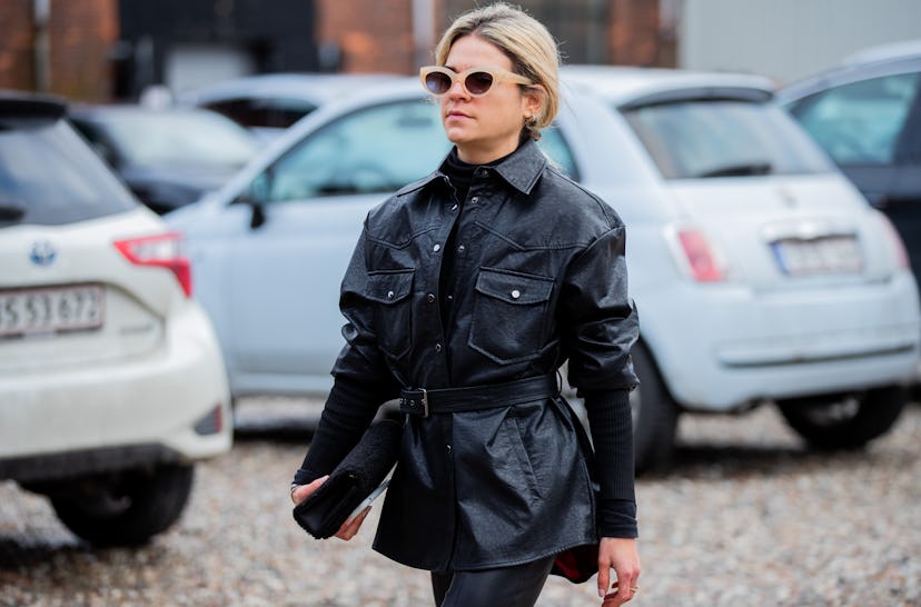 A woman in a black leather jacket, and black pants carrying a black purse at the Copenhagen Fashion ...