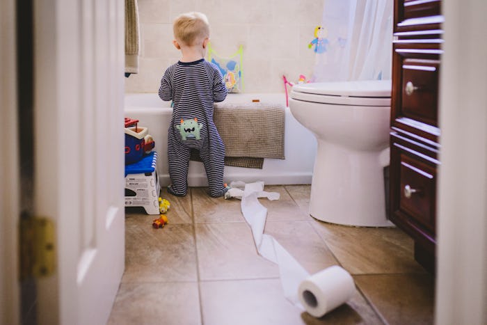 a toddler boy making a mess in the bathroom