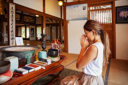 A young woman prays in a temple in Japan. 