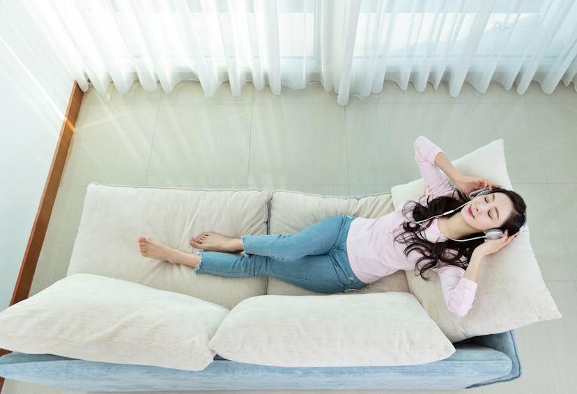 A woman lies down while listening to headphones. Human speech heard during sleep can affect dreams i...