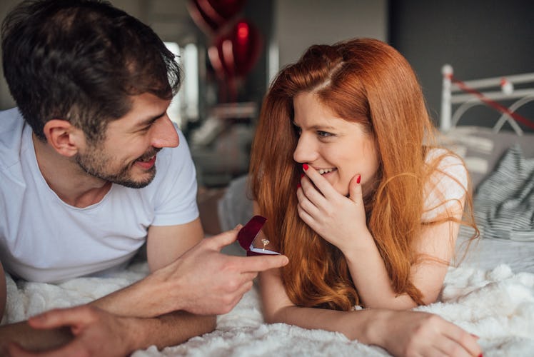 A man proposes to his girlfriend on Valentine's Day while they're laying in bed.
