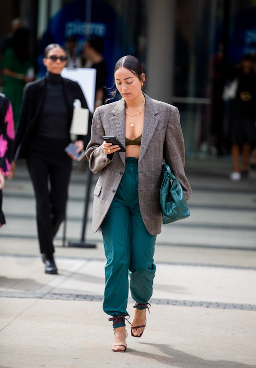 Rachael Wang in a plaid blazer, black bralette and high-waisted green pants with a matching bag 