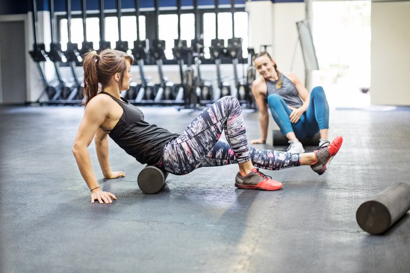 Two people foam roll together on the gym floor. Take it easy when you're coming back to the gym from...