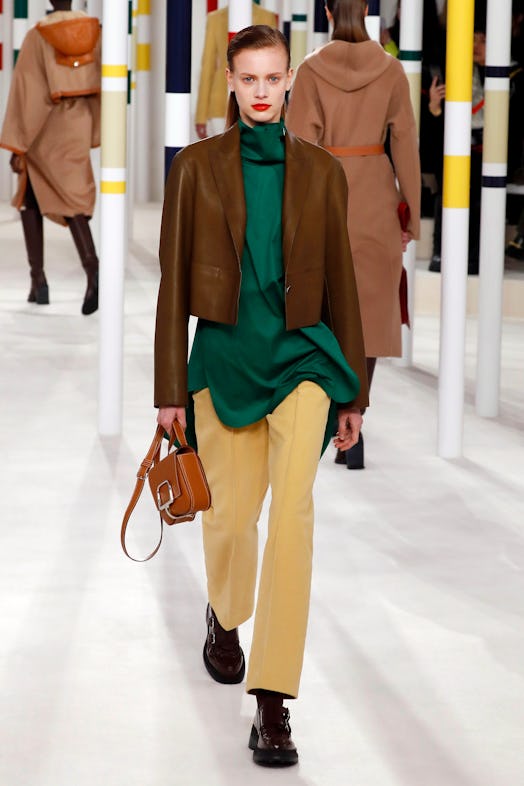 A model wearing a brown jacket with green shirt and yellow pants from Hermes' Fall 2020 Collection 