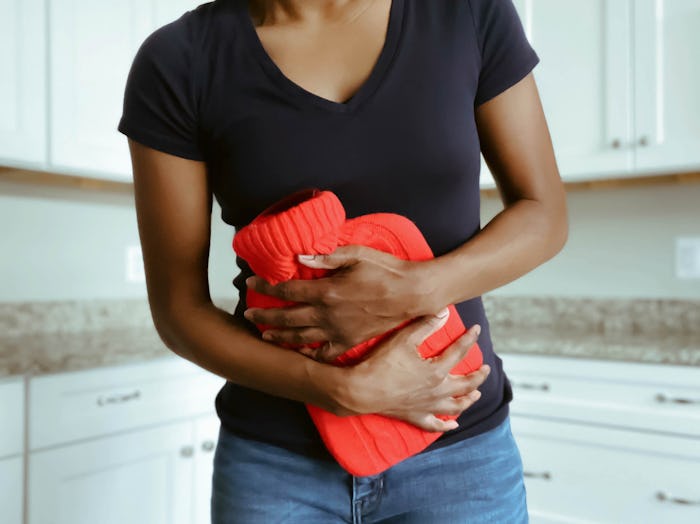 woman holding hot water bag to her abdomen