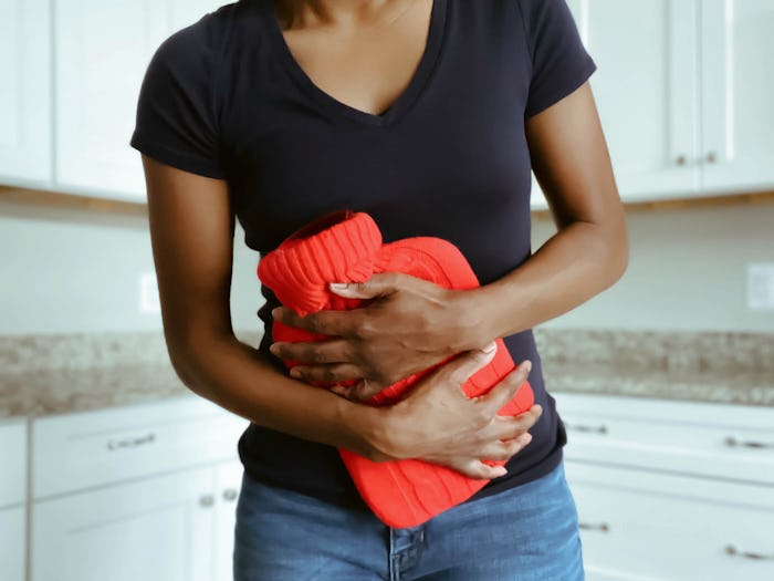 woman holding hot water bag to her abdomen