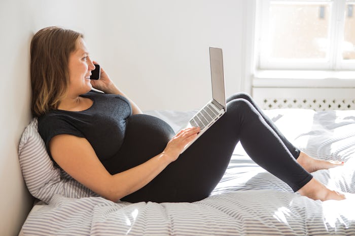 pregnant woman wearing leggings on bed