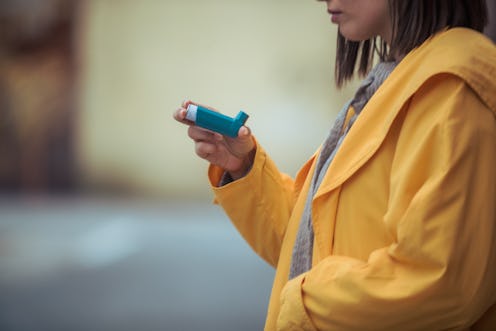 A person wearing a yellow jacket holds up their inhaler. It appears that people with asthma are not ...