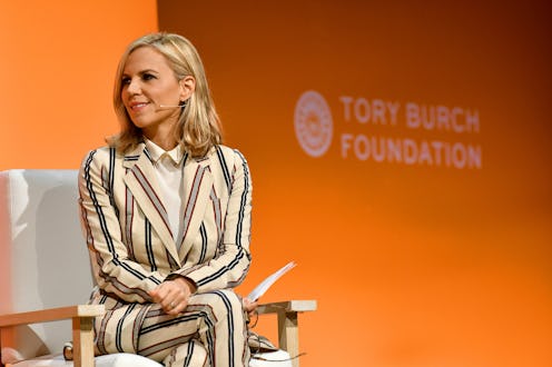 Tory Burch in a striped blue and white suit sitting at a chair for a tony burch foundation event