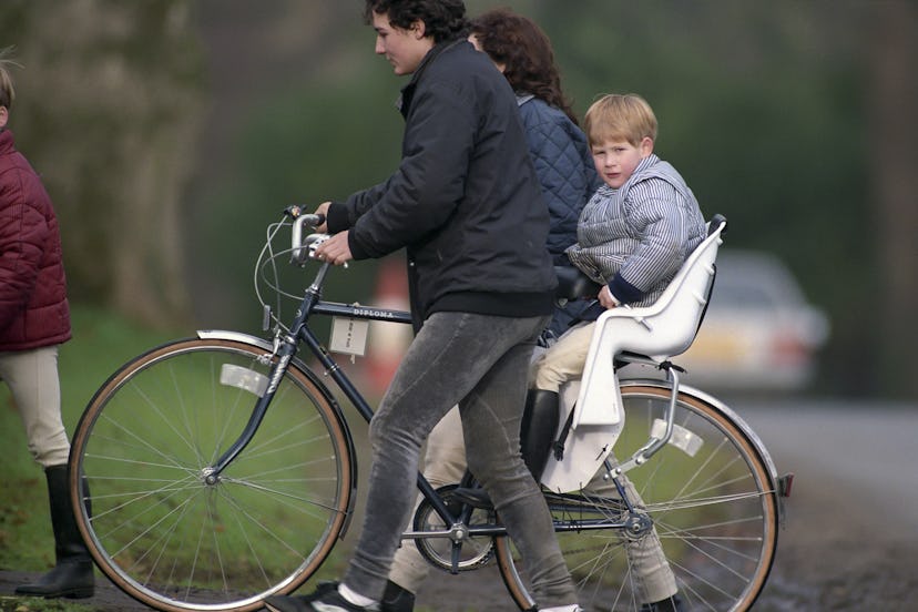 Prince Harry rides in a seat on a bike