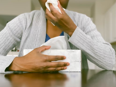 A woman blows her nose. During the coronavirus outbreak, paid sick leave is a major help to containi...