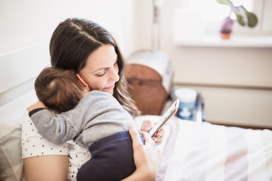 a mom on her iPhone holding infant