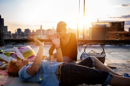 A young couple has a picnic on a rooftop in the city at golden hour.