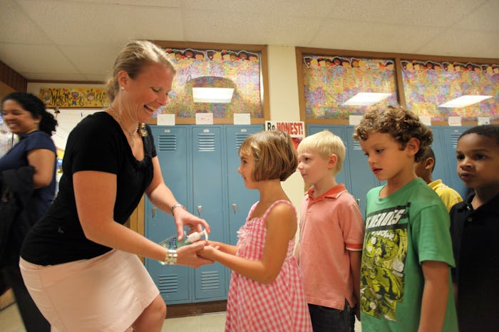 a teacher putting hand sanitizer on kids' hands