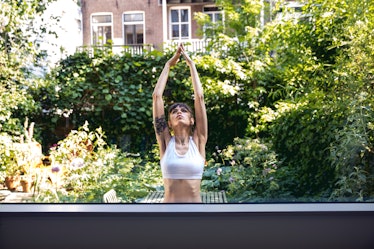 A woman does stretches and yoga poses in her backyard.