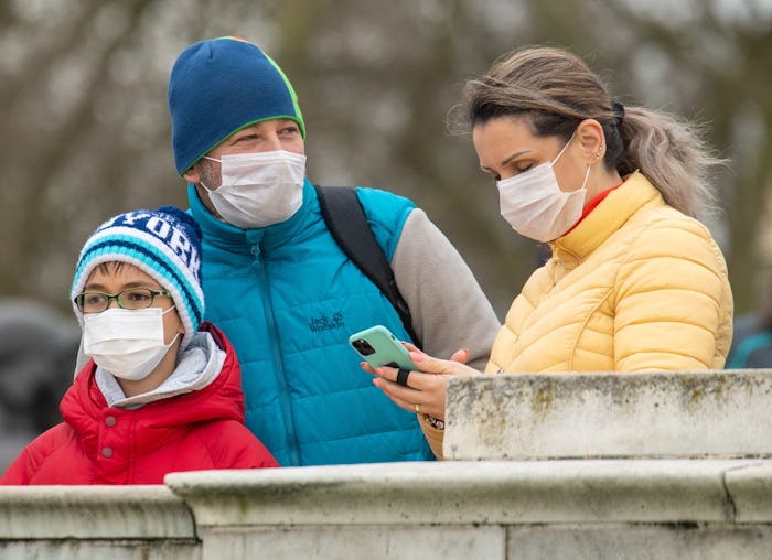 a mother, father, and son all wearing masks outside in a quarantine
