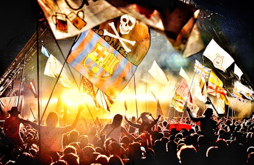 The stage and crowd at glastobnury with various flags flying in the air