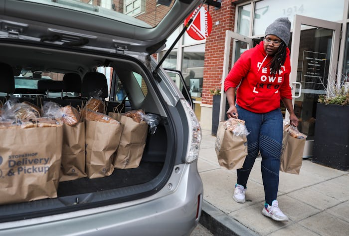 a woman packing food donations into the back of a car