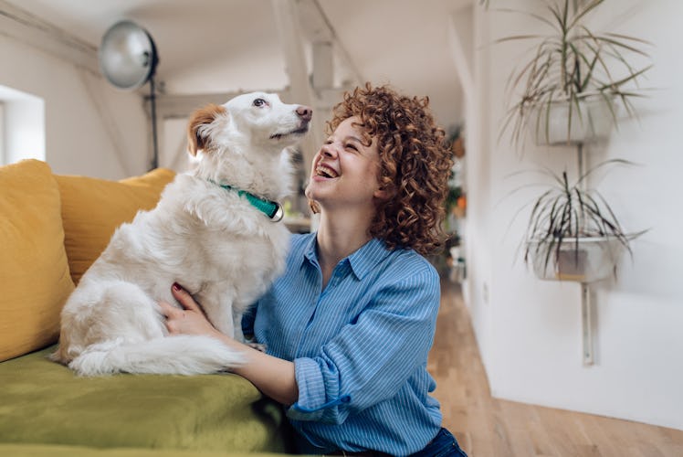 A girl laughs while hanging out at home with her dog.