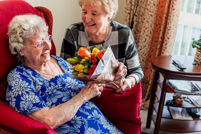 an elderly woman getting flowers in a nursing home