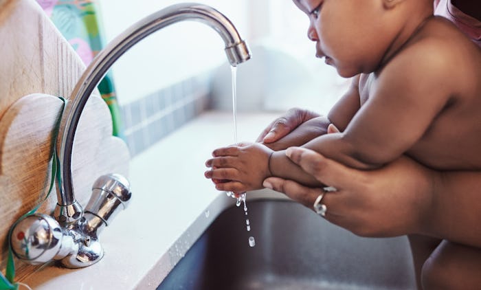 a mom washing her baby's hands in the sink