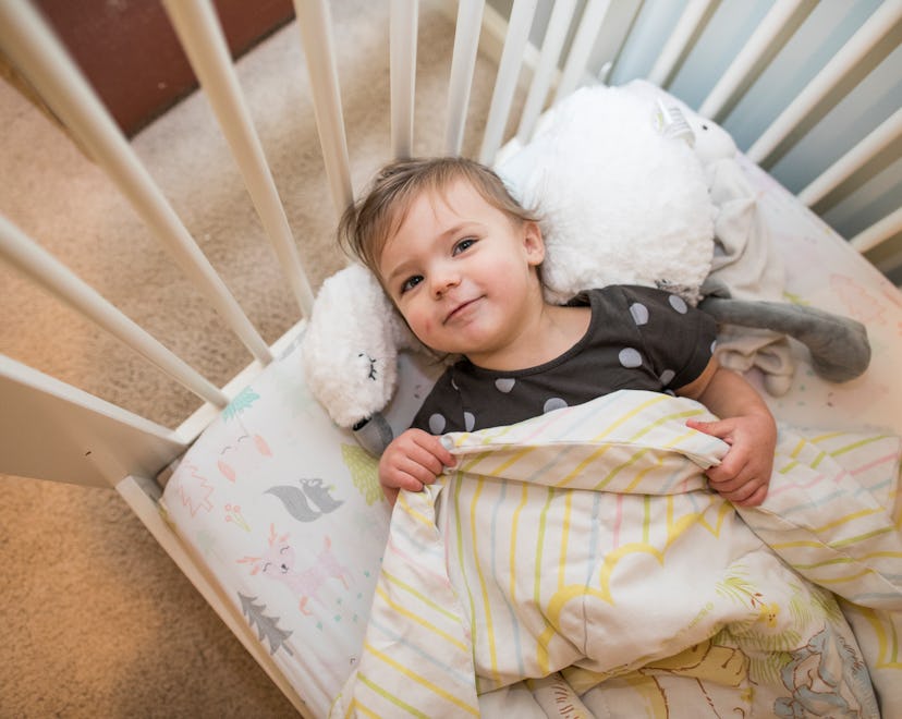 Toddler smiling in crib, in a story about what to do if toddler sleeps with blanket over head