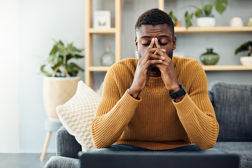 A man in a mustard sweater sitting in his living room and he has coronavirus anxiety