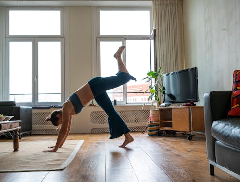 A person performs a down dog split in a living room. If you're concerned about the coronavirus in yo...