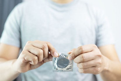 A man rips open a condom to have sex for the first time