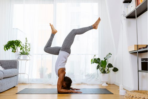 A person does yoga in her living room. You can work out at home even if you're socially distancing w...