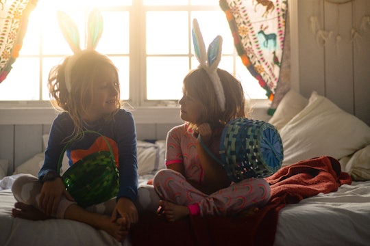 two sisters sitting on bed with easter baskets and bunny ears