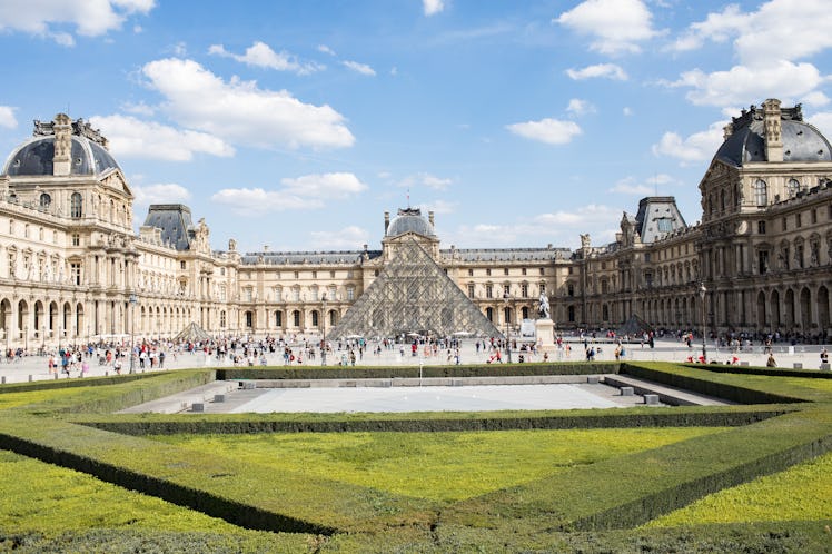 The Louvre in Paris is fairly crowded on a sunny day in the summer.