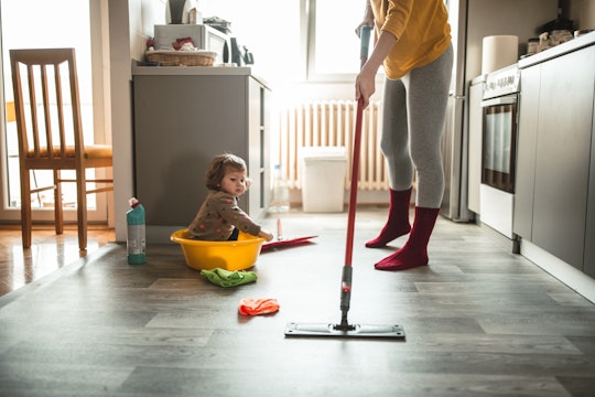 woman cleaning floor with baby watching
