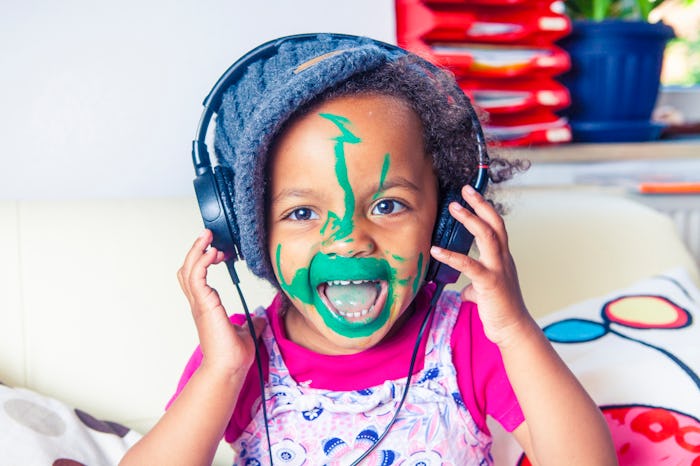 toddler singing with headphones and green paint on face