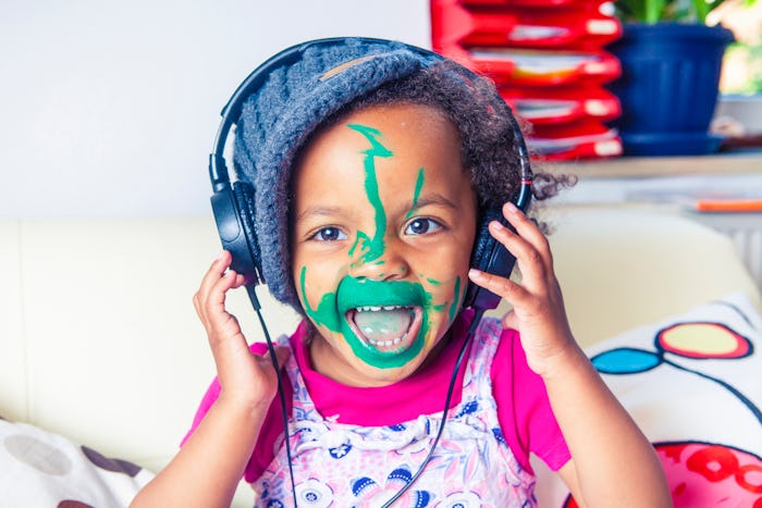 toddler singing with headphones and green paint on face