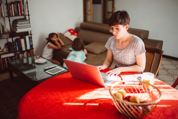 mom working from home as kids play in background